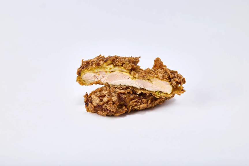 揚げられた鶏肉が半分にカットされた写真。鶏肉は衣で覆われており、内部の肉が見えています。