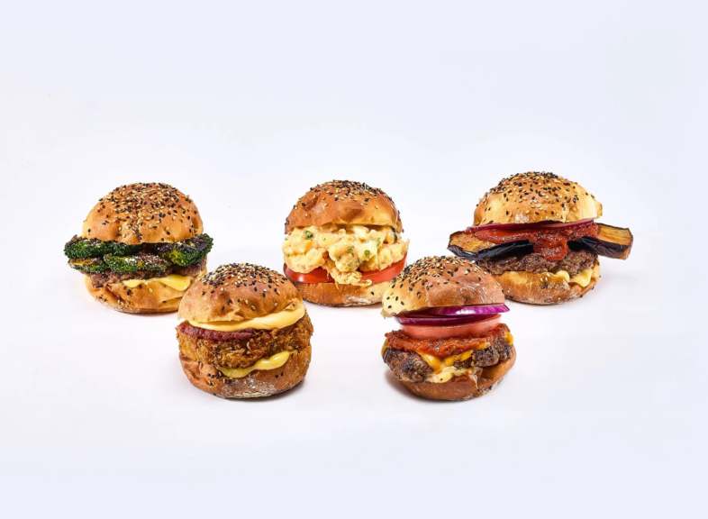 様々なハンバーガーが白背景に並んでいる写真です。ハンバーガーは、ブロッコリー、卵サラダ、ナス、赤玉ねぎ、トマトなど、様々な具材が使われています。