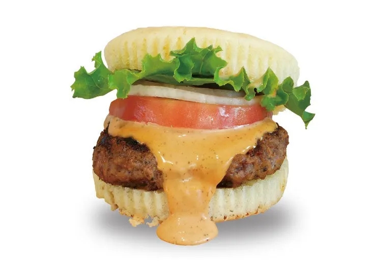 ハンバーガーのクローズアップ写真。バンズ、レタス、トマト、玉ねぎ、パテ、ソースが写っています。