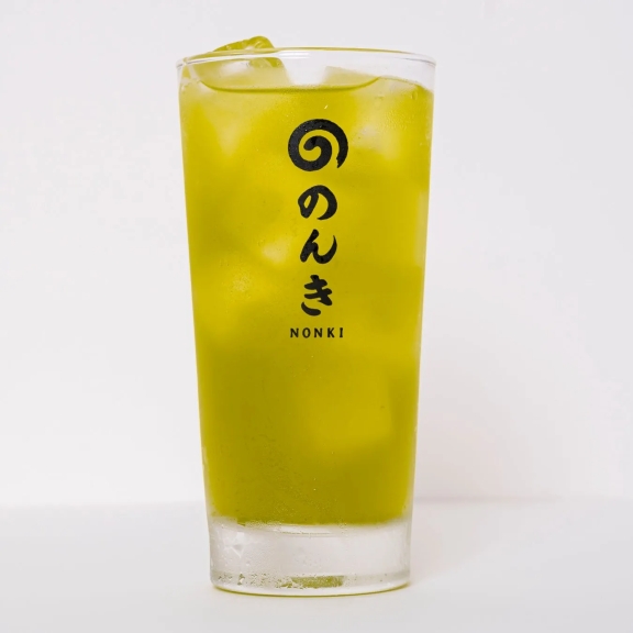 グラスに入った抹茶のような緑色のドリンク。氷が入っており、ロゴが印字されている。