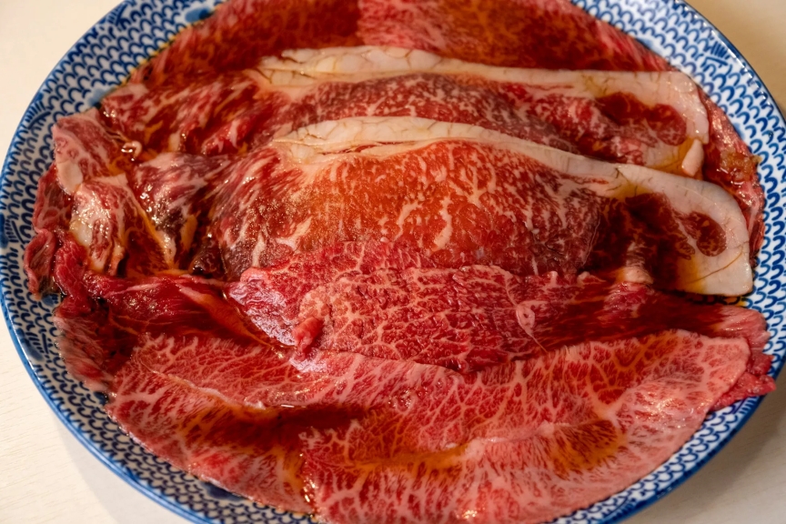お皿に盛られた、霜降りの牛肉のクローズアップ画像です。赤身と脂肪のバランスがとれた、美味しそうな牛肉が写っています。