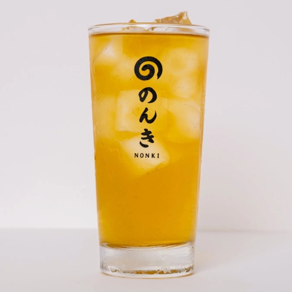 グラスに入った、氷の入った黄色い飲み物の写真です。「のんき」という文字が書かれています。