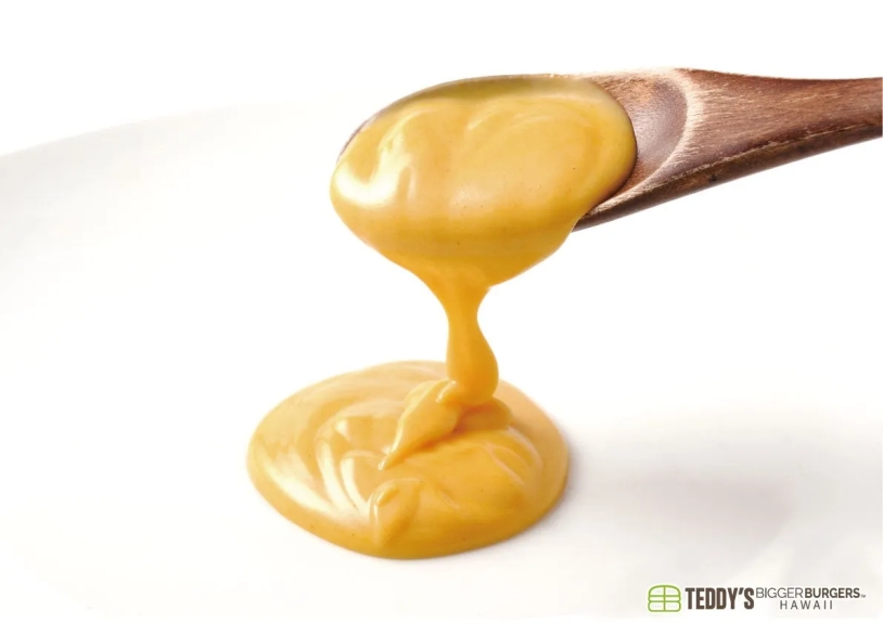 木製のスプーンからとろけるように流れ出る黄色のソース。