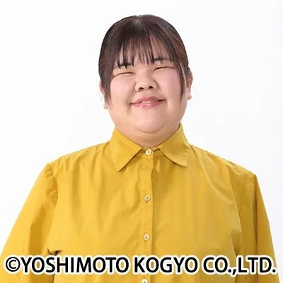 笑顔で目を閉じた女性のポートレート。黄色いシャツを着ていて、背景は白い。