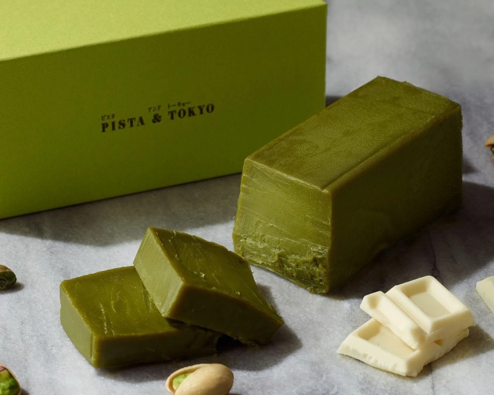 ピスタ＆トーキョーの抹茶スイーツの画像。抹茶色の四角いケーキがいくつかあり、白いチョコレートも添えられている。緑色の箱にはブランド名が書かれている。