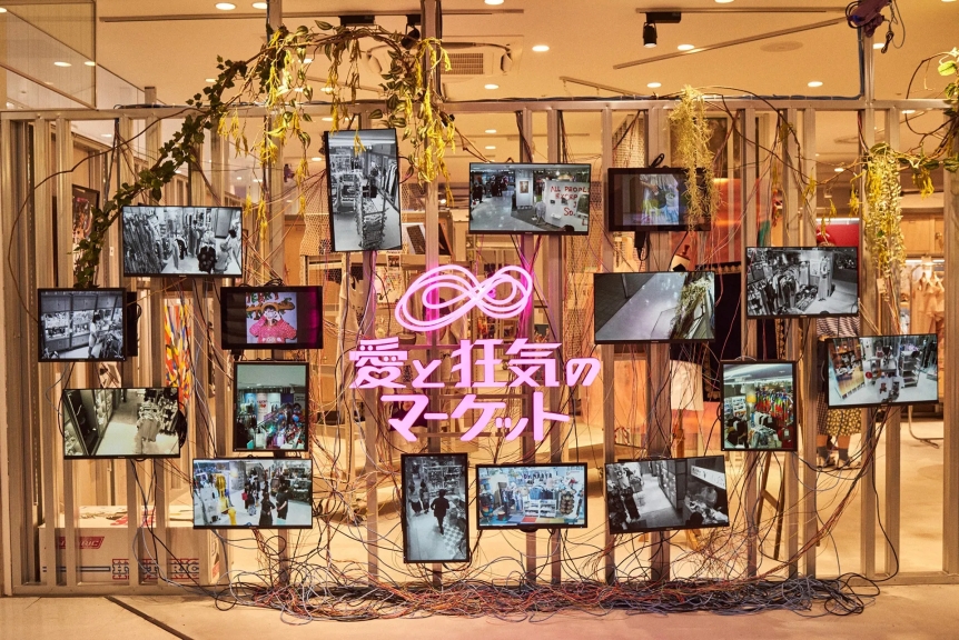 店内ディスプレイ。複数のモニターに映像が映し出され、ネオンサインで文字が装飾されている。