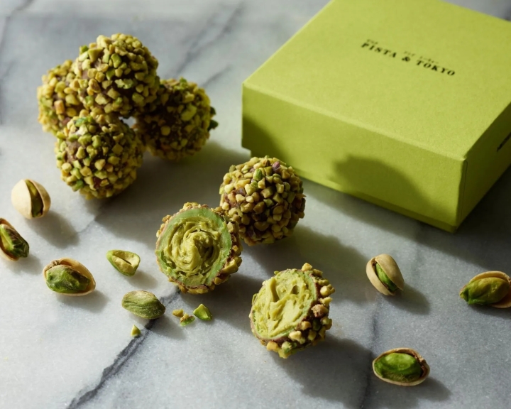 ピスタチオトリュフとピスタチオの画像。トリュフはピスタチオでコーティングされ、半分にカットされたものもある。箱には「PISTA & TOKYO」のロゴが入っている。