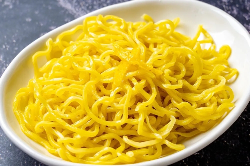 白い器に入った黄色い麺のクローズアップ写真です。