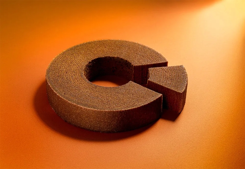 バウムクーヘンが置かれた写真。バウムクーヘンの一部が切り取られており、オレンジ色の背景に配置されています。