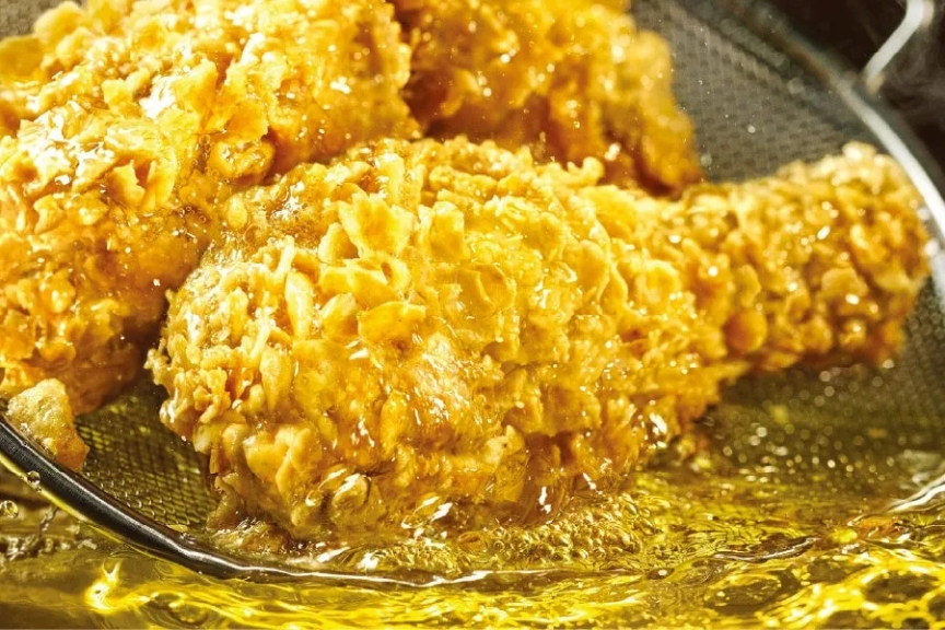 揚げたてのフライドチキン。油の中に浸かっている様子。