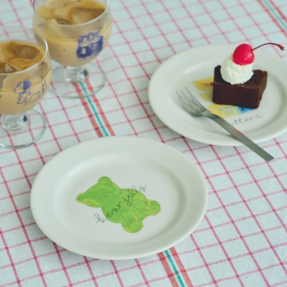 テーブルの上に、アイスコーヒー、ケーキ、クマの絵が描かれた皿