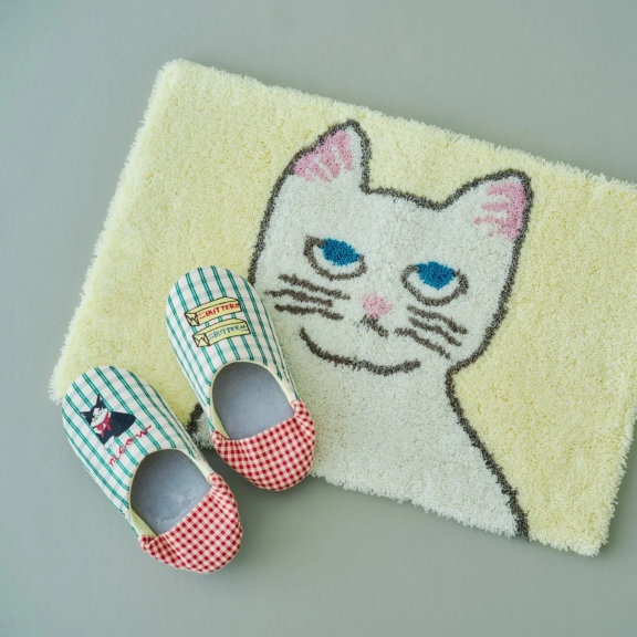 猫の顔が描かれたバスマットと、猫のイラストが入ったスリッパ