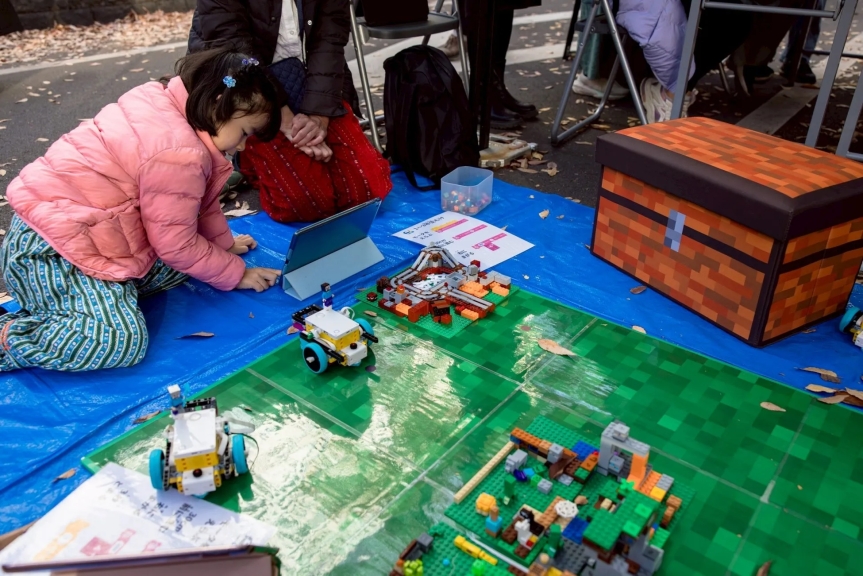 レゴブロックで作られたコースで遊ぶ女の子の様子。タブレットを操作し、レゴロボットを動かしている。