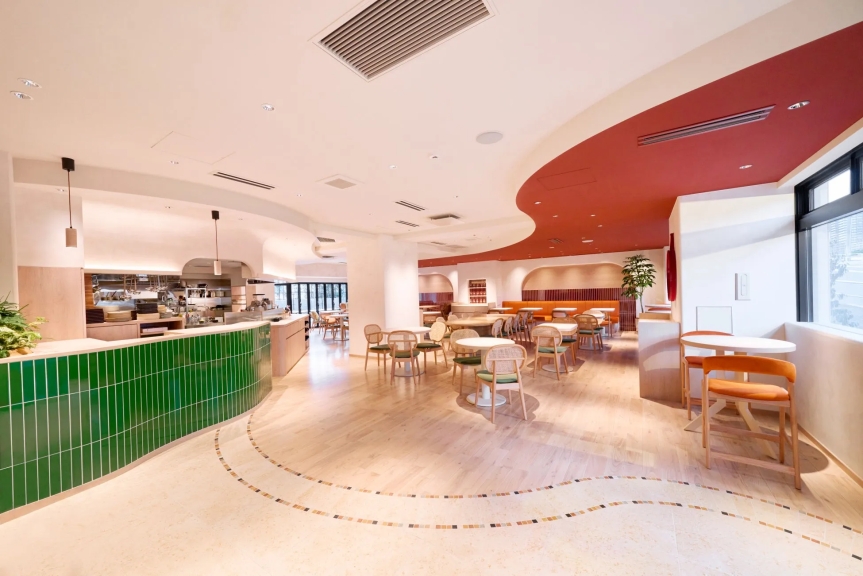 モダンなレストランのインテリア。緑のタイル張りのカウンター、木製の床、丸いテーブルと椅子が配置され、赤い天井がアクセントになっています。