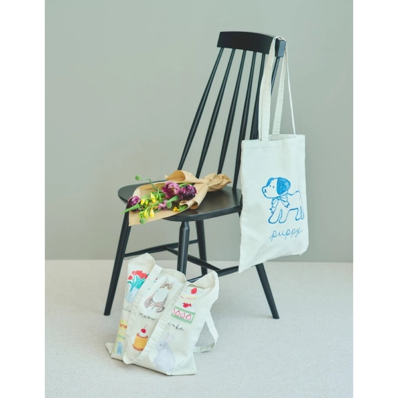 黒い椅子に花束と、犬のイラストが描かれたトートバッグ