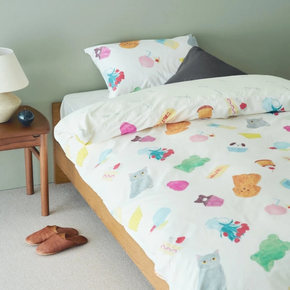 ベッドに猫や食べ物のイラストが描かれた布団と枕