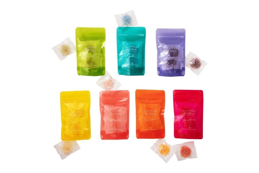 さまざまな色のパッケージに入った砂糖菓子が並んだ写真。パッケージには「GLITTER BIJOUX」の文字と、フレーバー名が書かれています。砂糖菓子はそれぞれ花のような形をしており、透明な袋に入っています。
