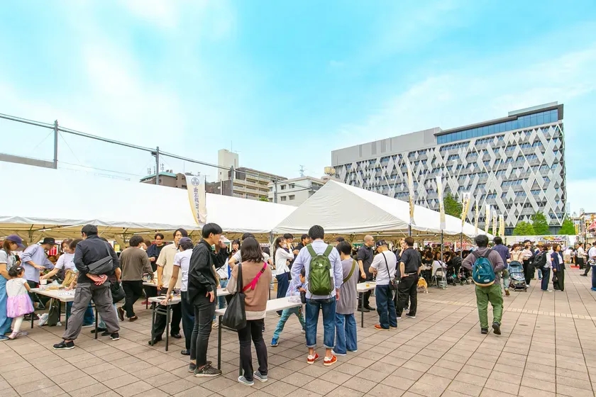 お祭り会場の様子。多くの人がテントの下で食事やイベントを楽しんでいます。